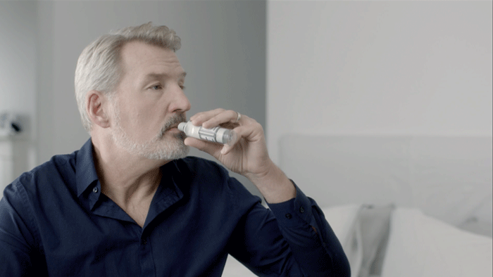 Close-up of a man holding and using the Respimat inhaler