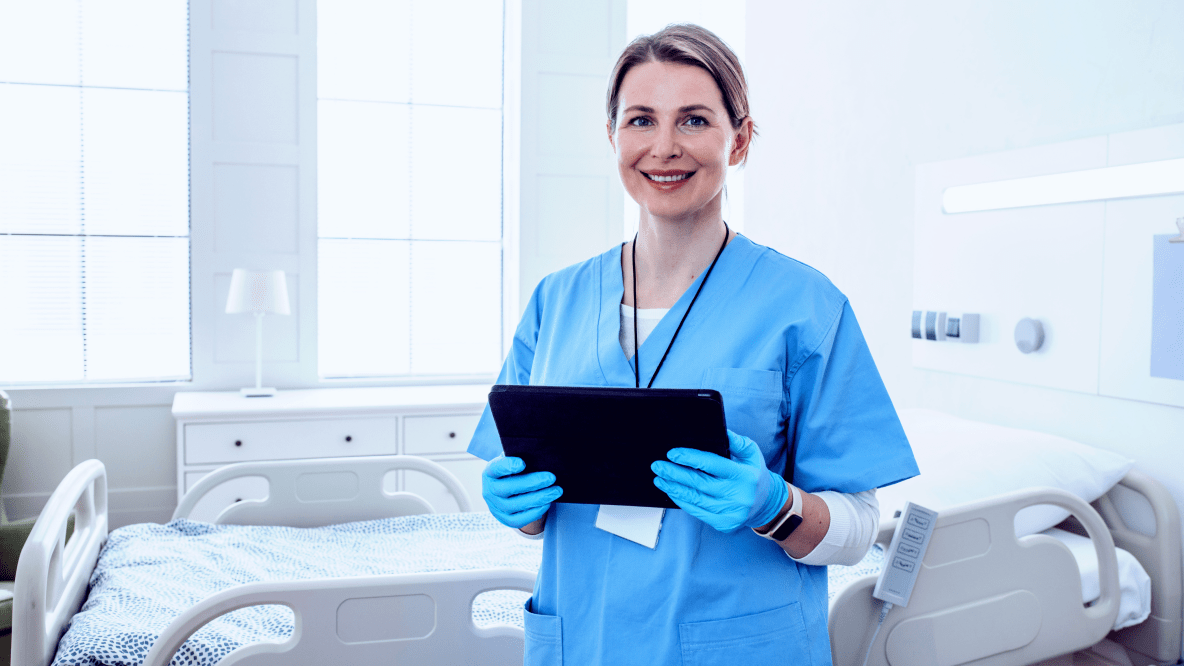 Doctor in blue scrubs holding clipboard beside hospital bed