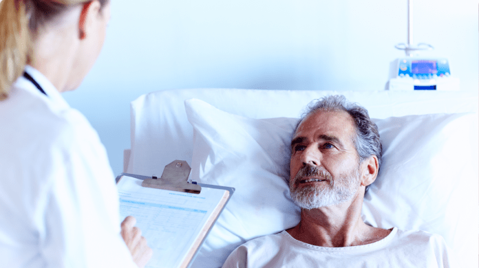 Doctor with clipboard talking to patient in hospital bed