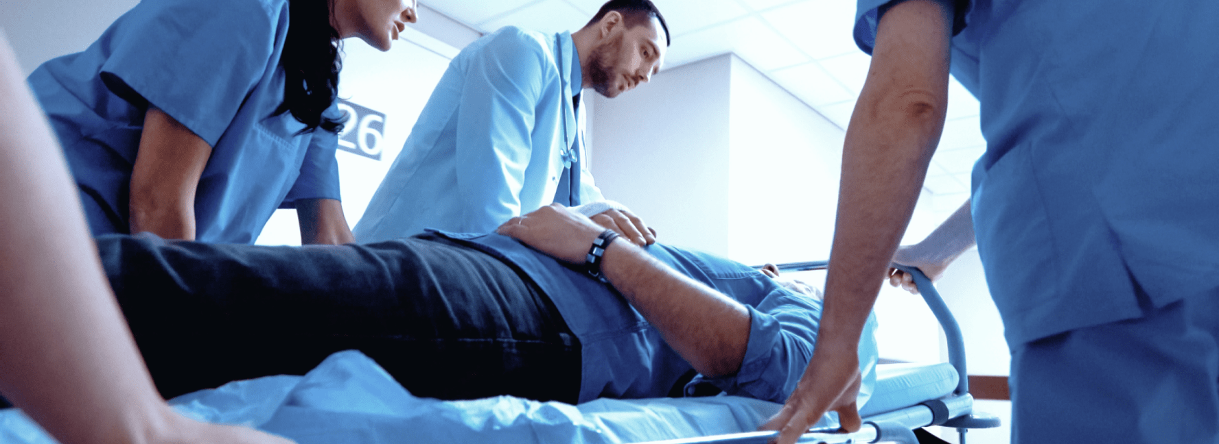 Three doctors wheeling patient on a stretcher