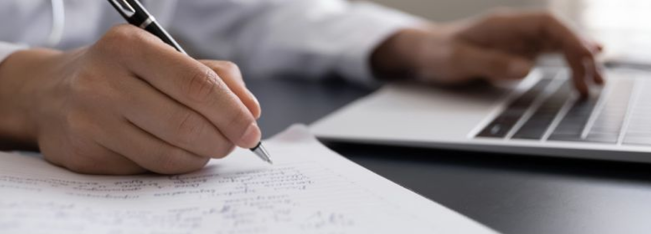 A man using a laptop and taking notes